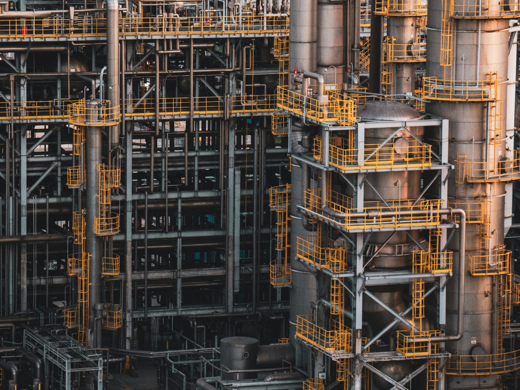 Industrial refinery infrastructure with yellow railings and steel piping